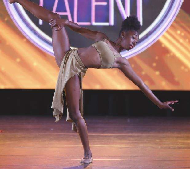 A dancer reaching her hand to her left